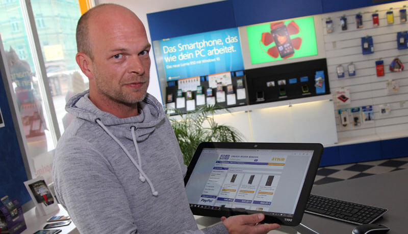 aetka Fachhändler im Geschäft mit Tablet in der Hand, welches den ebay Shop zeigt