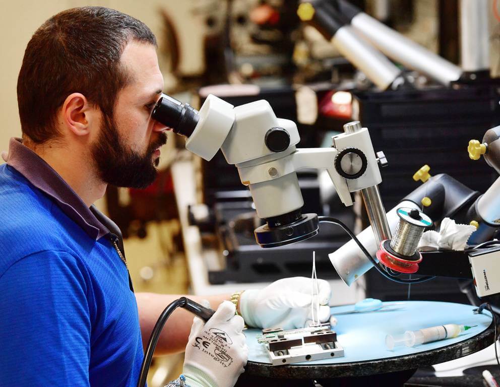 Mitarbeiter der aetka sitzt am Reparaturplatz für Smartphones